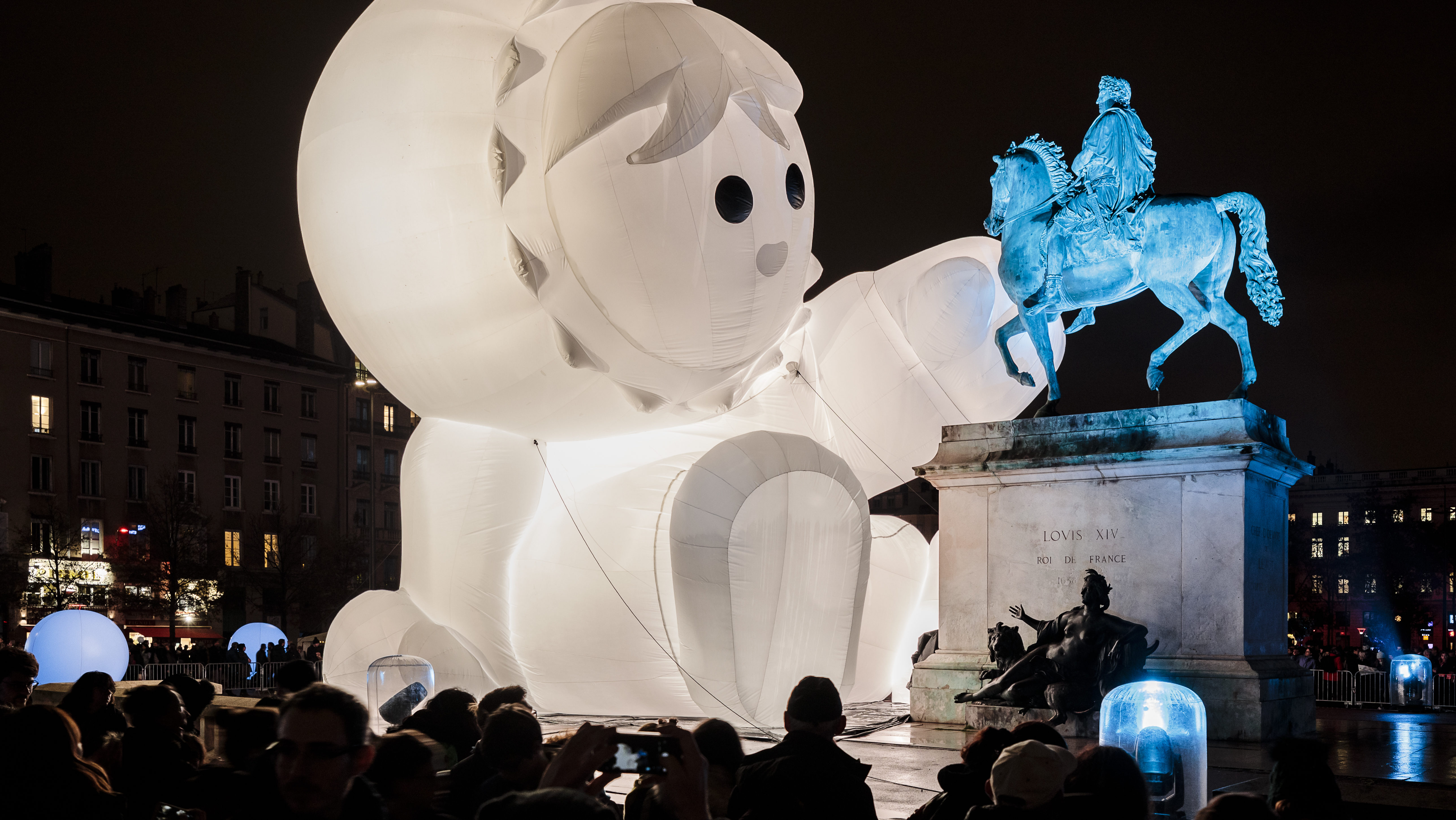 A giant inflatable character plays with the statue of Louis XIV in Lyon